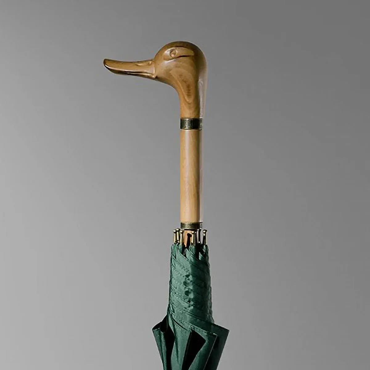 Detailed close-up of the hand-carved natural wood duck head handle on the green stick umbrella.
