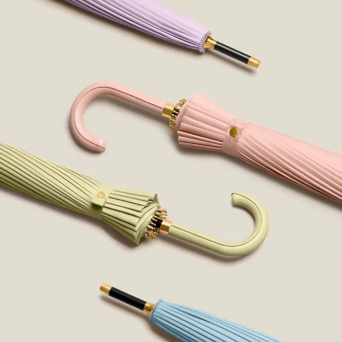 Several closed 24-rib ladies umbrellas in pastel colors, showing their sleek profile and leather handles.