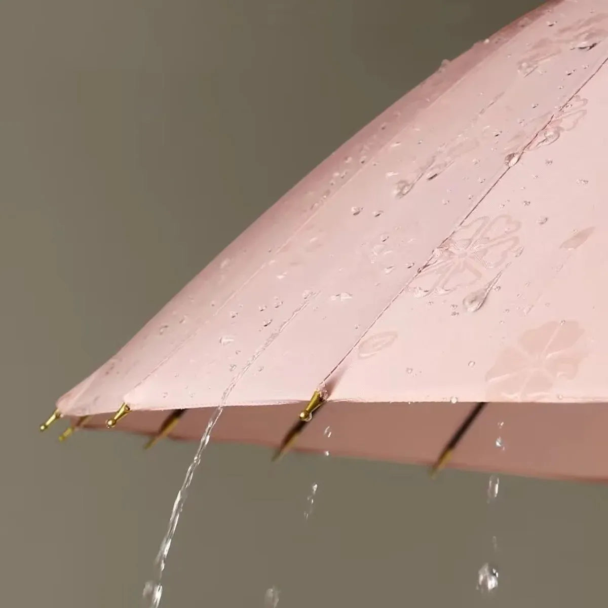Water droplets on the pink canopy revealing the magic color-changing floral pattern of the 24-rib umbrella.