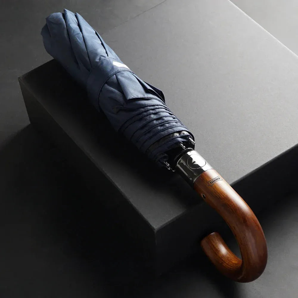 The 48-inch automatic folding umbrella with a wooden hook handle, shown closed in navy blue.