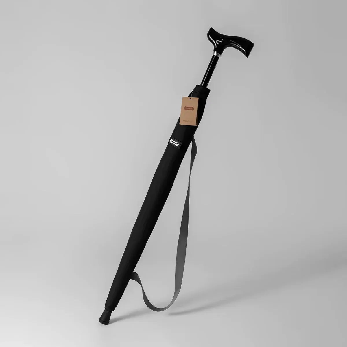 The adjustable walking stick umbrella in black, shown in its carrying sleeve with a shoulder strap.