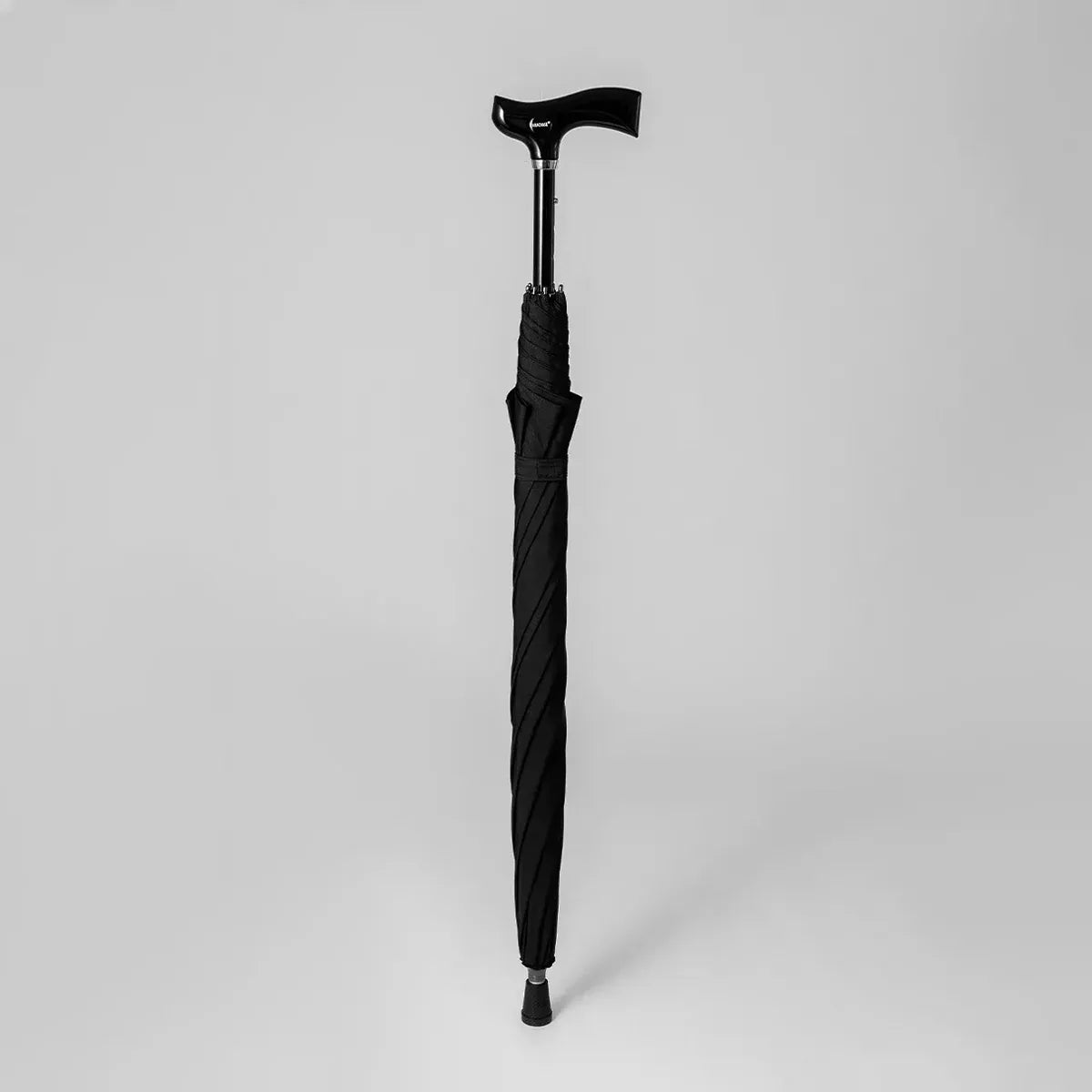 Profile view of the black adjustable walking stick umbrella when closed, showing the ergonomic derby handle.