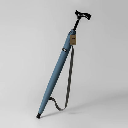 The adjustable walking stick umbrella in light blue, shown in its carrying sleeve with a shoulder strap.