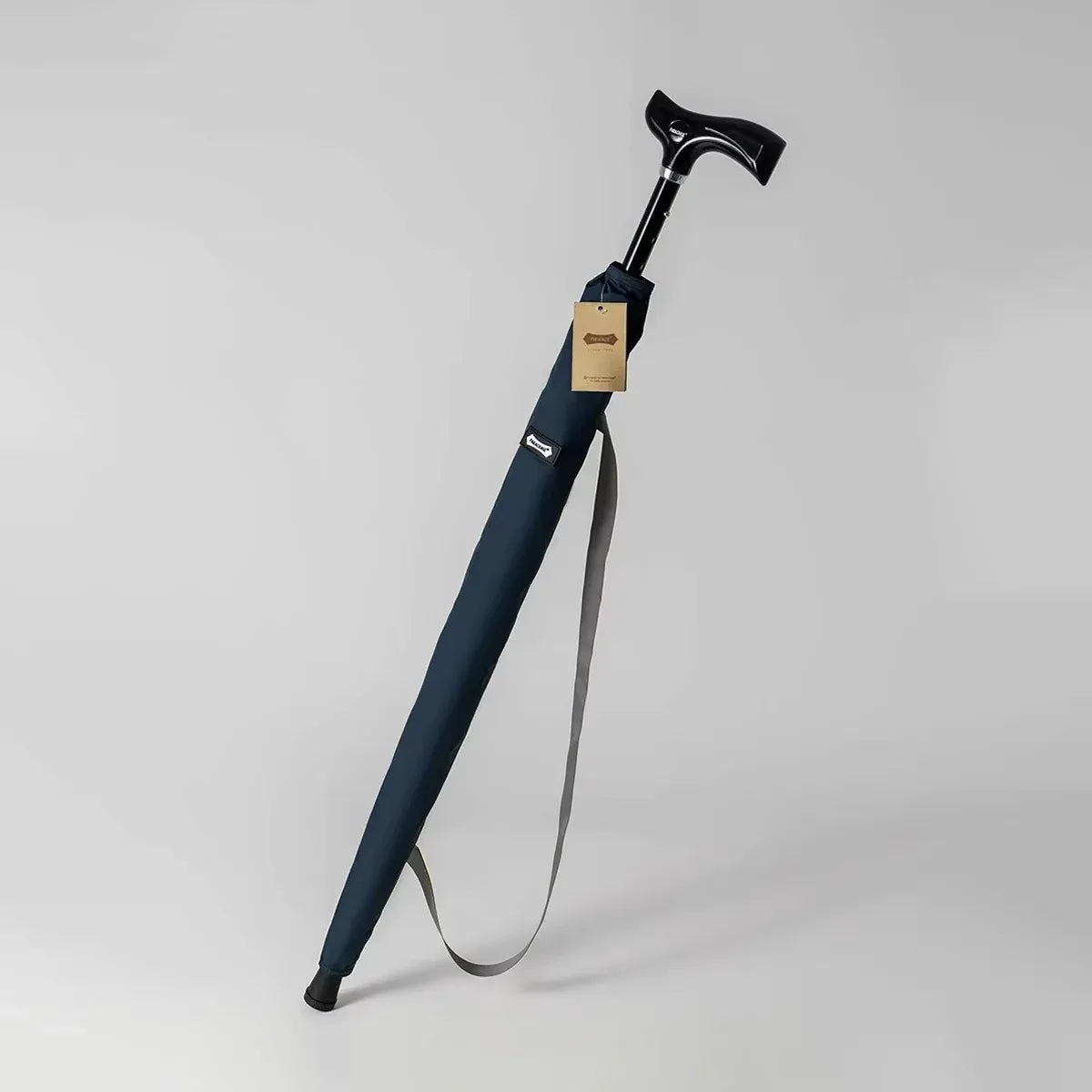 The adjustable walking stick umbrella in navy blue, shown in its carrying sleeve with a shoulder strap.