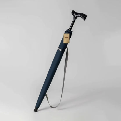 The adjustable walking stick umbrella in navy blue, shown in its carrying sleeve with a shoulder strap.