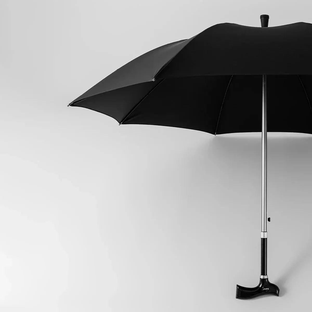 The adjustable walking stick umbrella partially open, displaying the large black canopy and sturdy aluminum shaft.