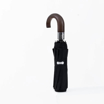 The automatic folding umbrella with a wooden hook handle, shown closed in a classic black color.
