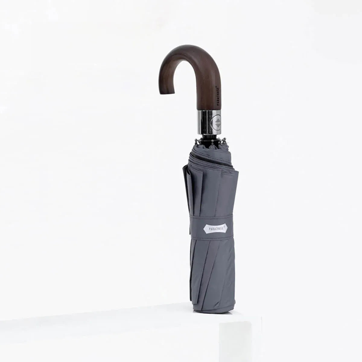 The automatic folding umbrella with a wooden hook handle, shown closed in a modern grey color.
