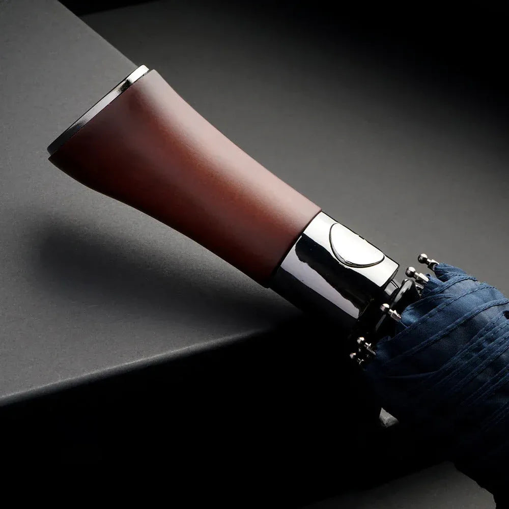 A detailed close-up of the polished wood handle and automatic button on the navy blue umbrella.