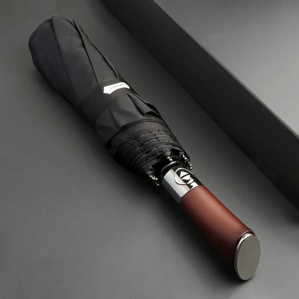 Profile view of the closed black automatic folding umbrella, highlighting the ergonomic wood handle.