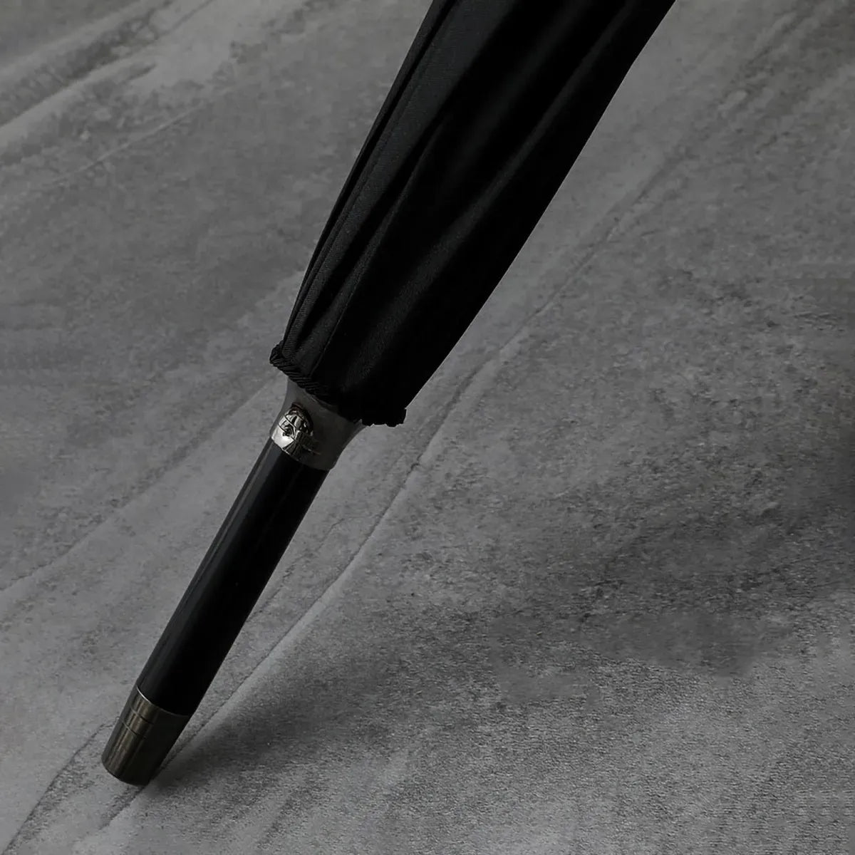 Detailed close-up of the polished metal tip (ferrule) at the end of the closed classic stick umbrella.