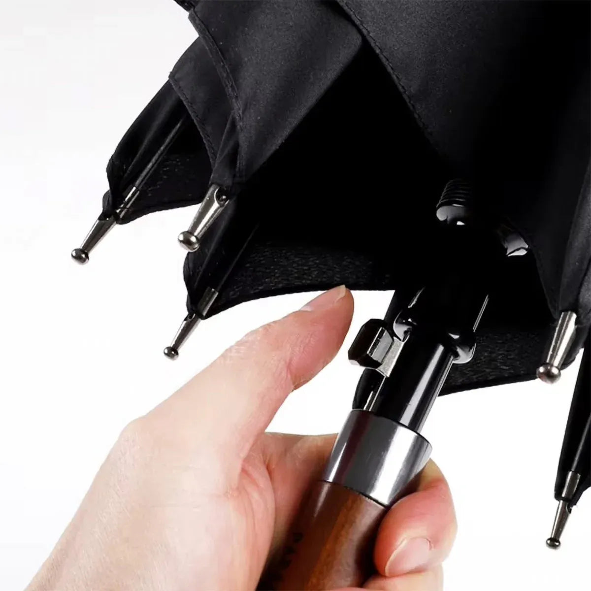 A hand pressing the semi-automatic open button located on the shaft above the wooden handle.