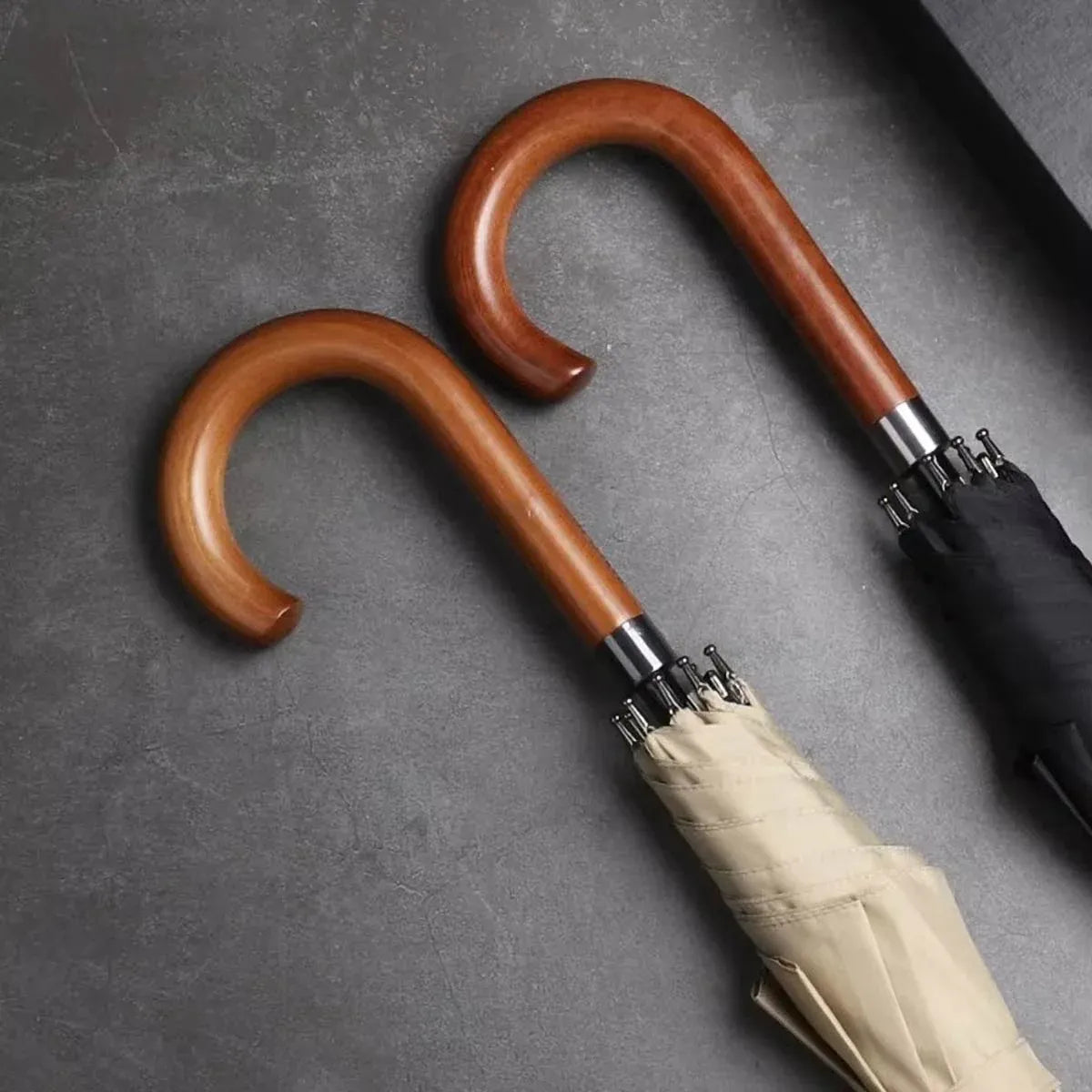 A detailed close-up of the solid wooden crook handles on the beige and black classic stick umbrellas.