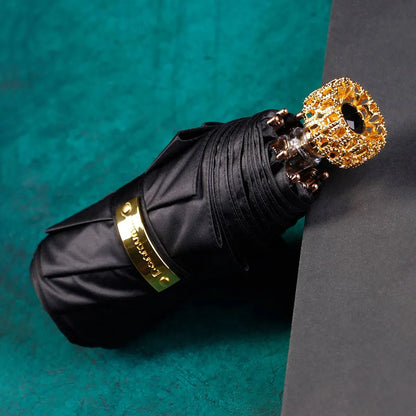 The compact luxury mini umbrella in black, showcasing the ornate golden handle with a black crystal.