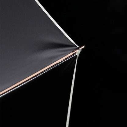 Close-up detail of the canopy tip and golden rib end on the compact luxury umbrella.