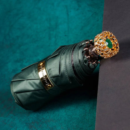 The compact luxury mini umbrella in green, showcasing the ornate golden handle with an emerald crystal.