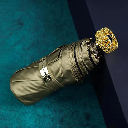 The compact luxury mini umbrella in olive green, showcasing the ornate golden handle with an amber crystal.