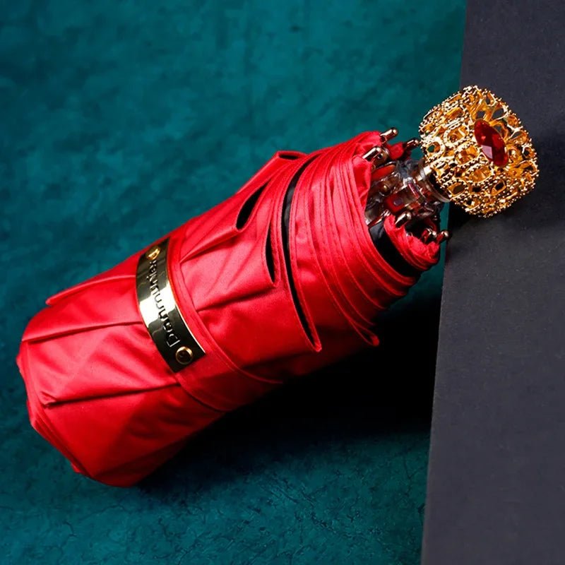 Compact luxury mini umbrella in red, featuring golden handle and crystal accent.