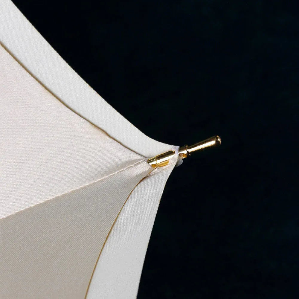 Close-up of the golden metal tip detail on the edge of the white umbrella canopy.