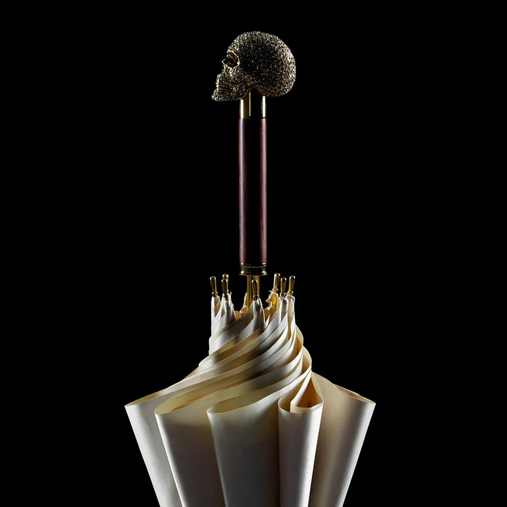 Detailed shot of the closed white canopy and the jeweled golden skull handle against a black background.