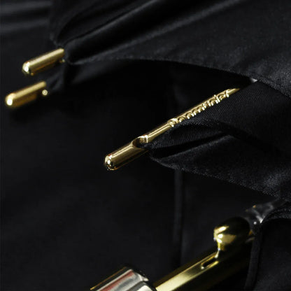 Detail shot of the elegant gold metal tips on the edge of the closed black canopy.