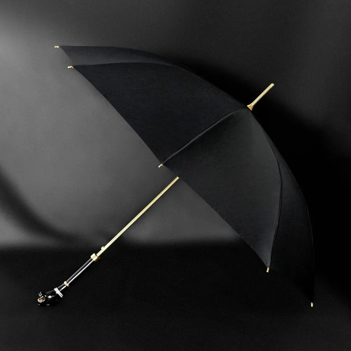 Angled profile view of the open elegant black umbrella, highlighting the gold shaft and panther handle.