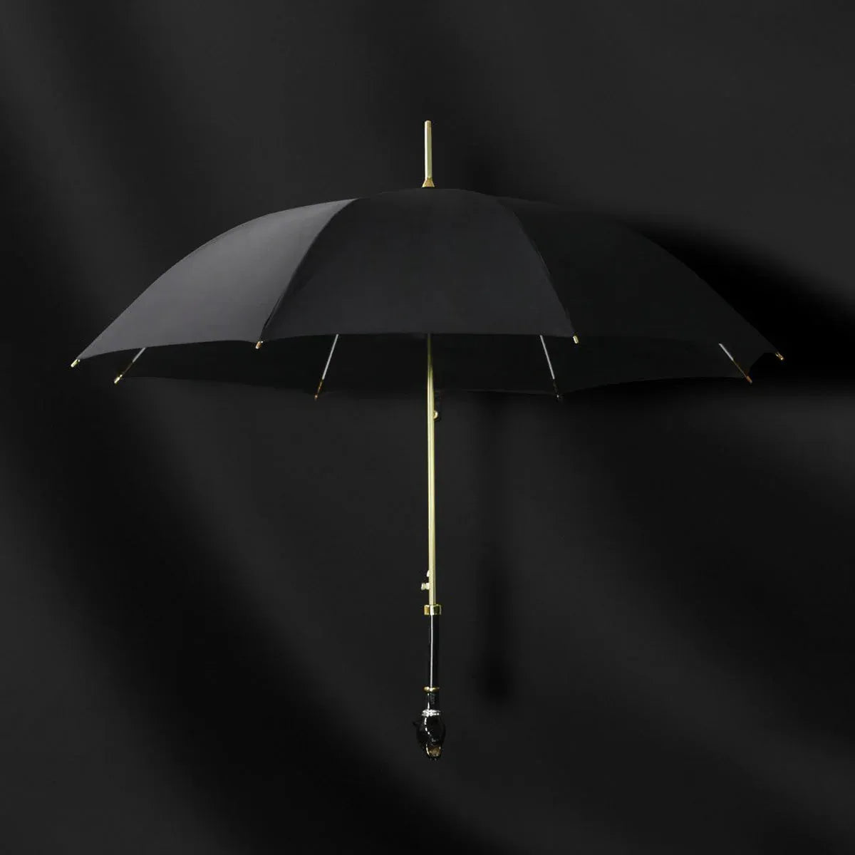 Front view of the open elegant black umbrella with gold accents and panther head handle.