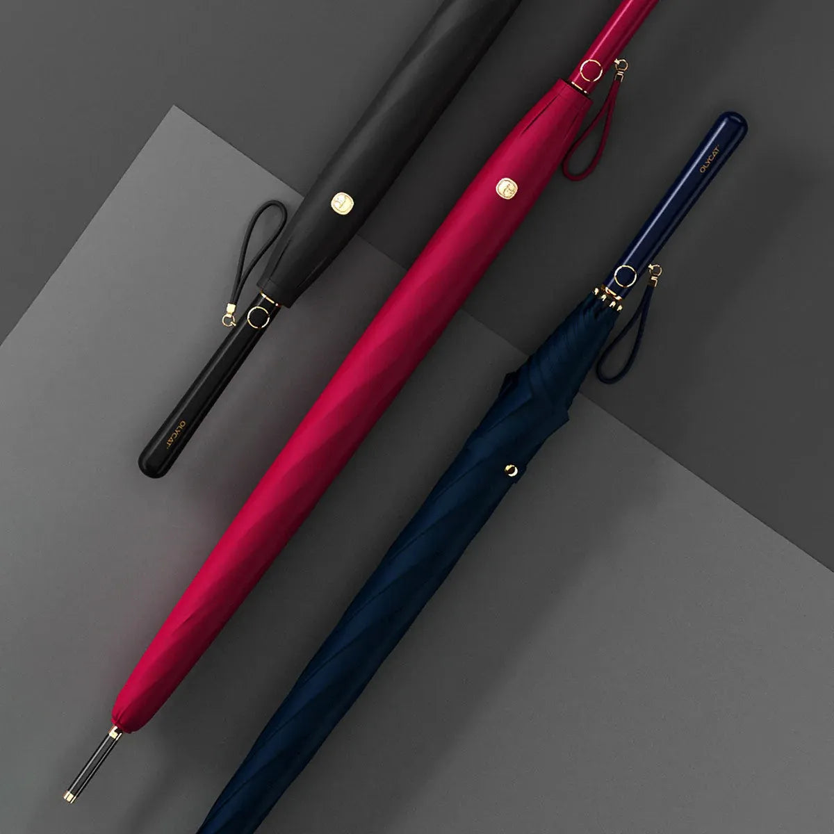 Lifestyle arrangement of the elegant long handle umbrellas closed, in black, red, and navy.