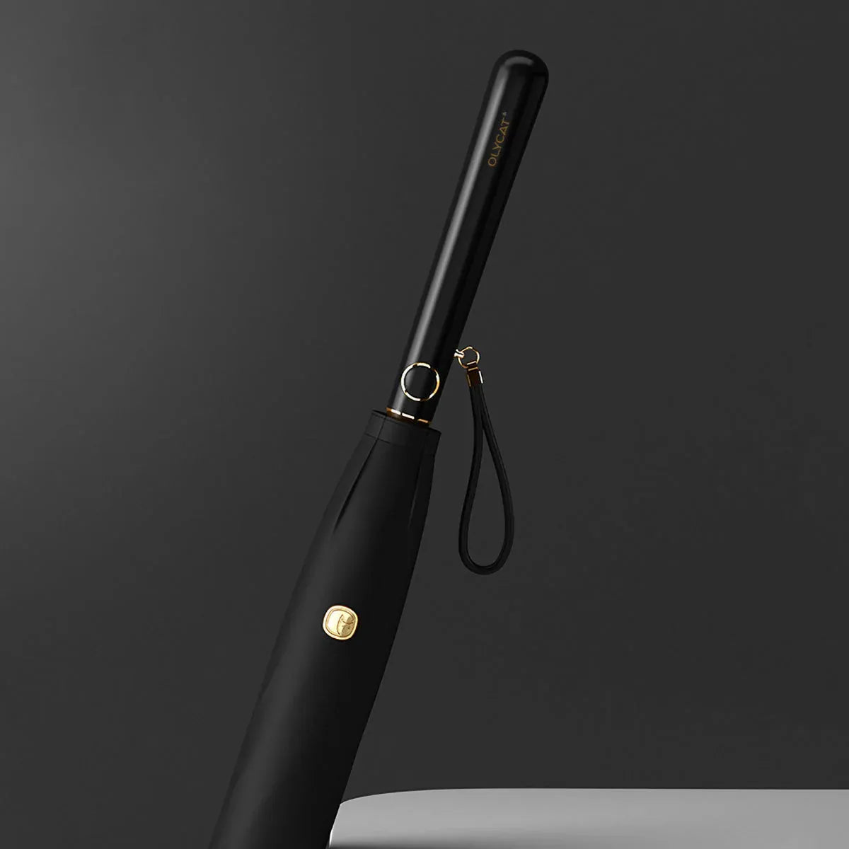 Close-up of the sleek black plastic handle with gold accents and wrist strap.