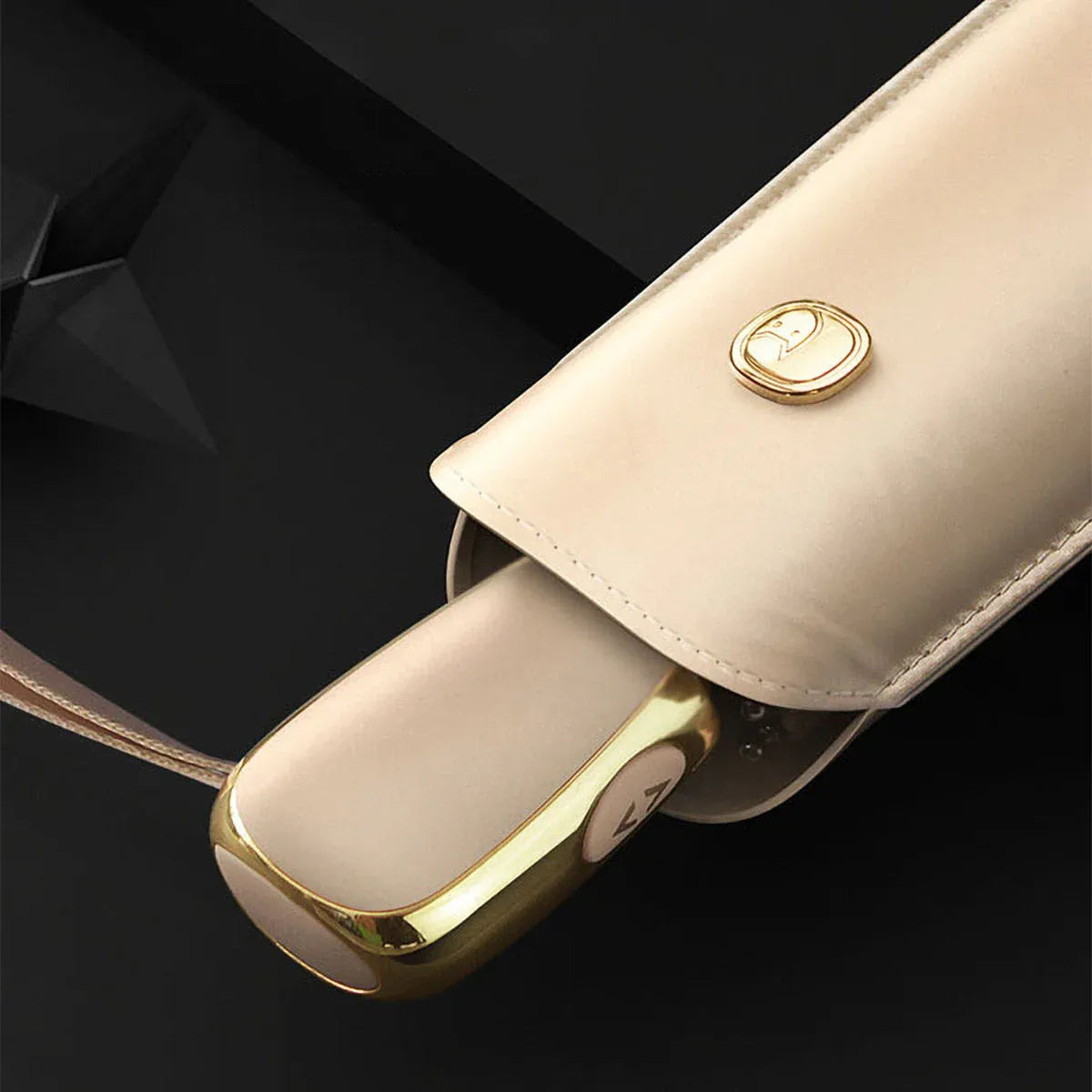 Detail shot of the beige travel umbrella handle partially emerging from its matching sleeve.