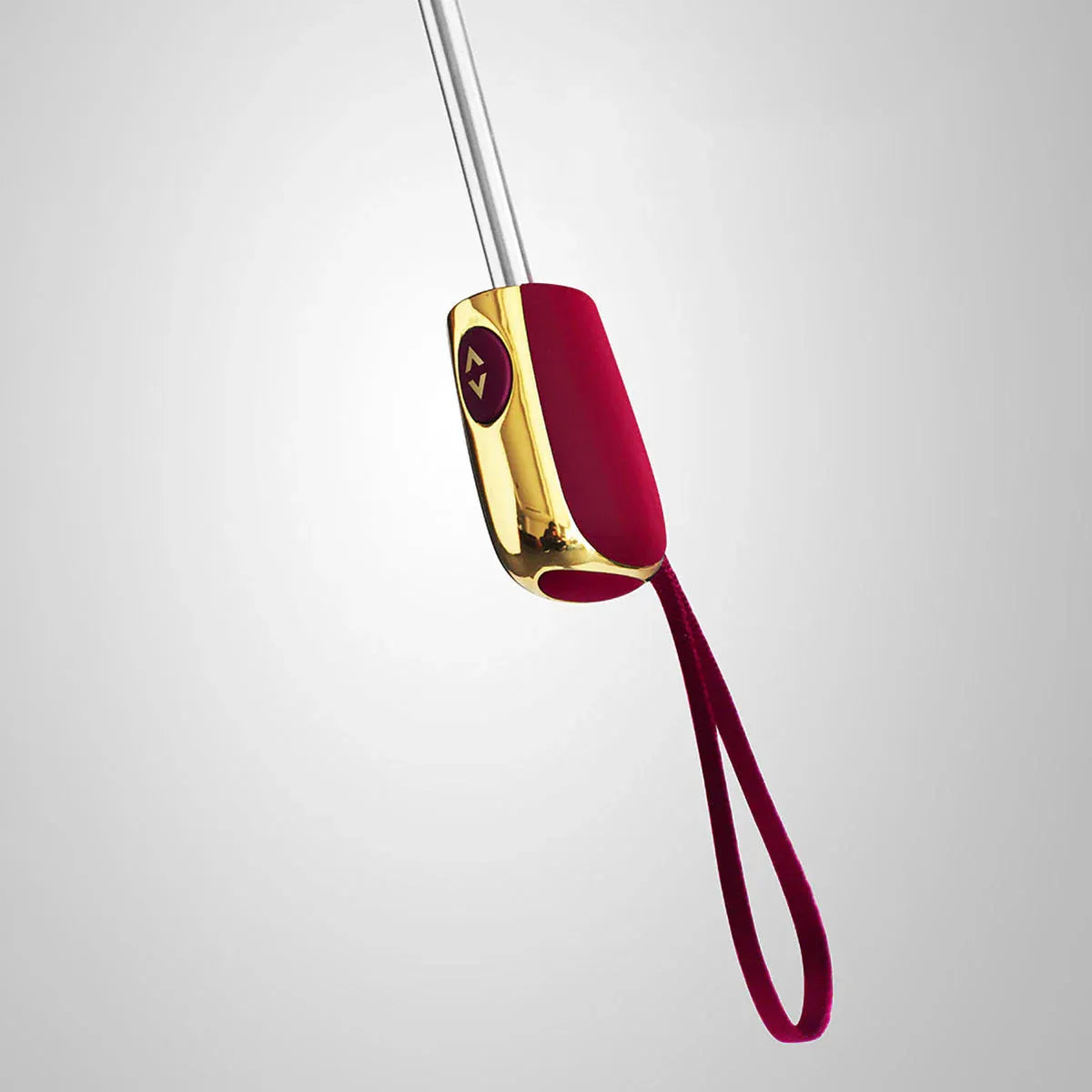 Close-up of the elegant red handle with gold accents and wrist strap on the travel umbrella.