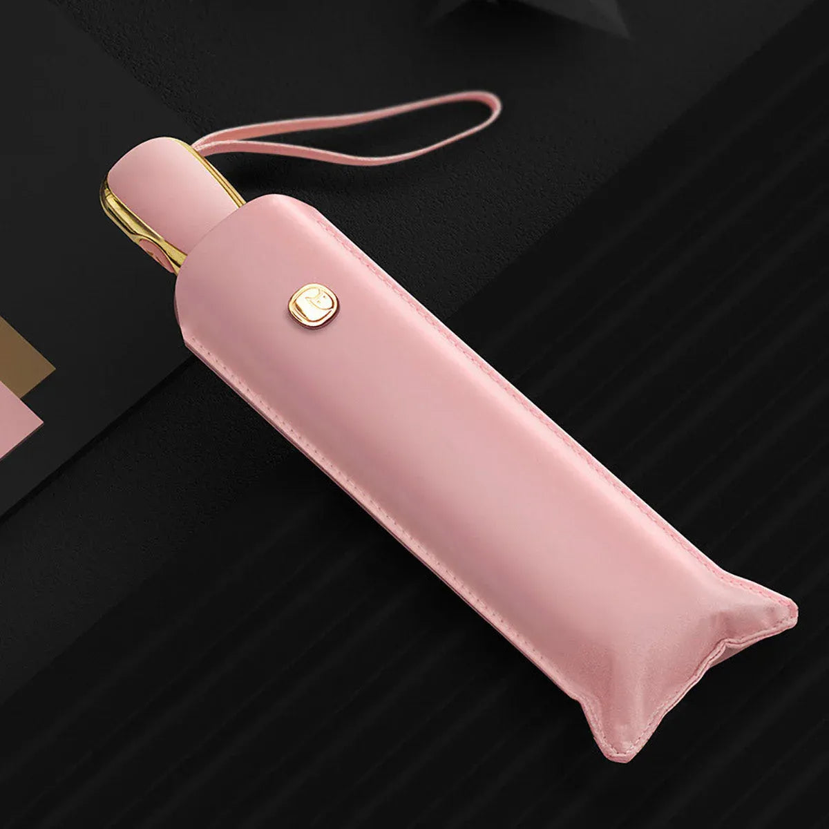 The elegant automatic travel umbrella for women in pink, shown closed in its matching sleeve.