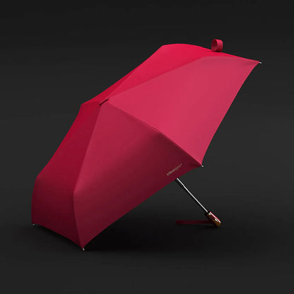 The lightweight elegant travel umbrella for women shown open in red color against a dark background.