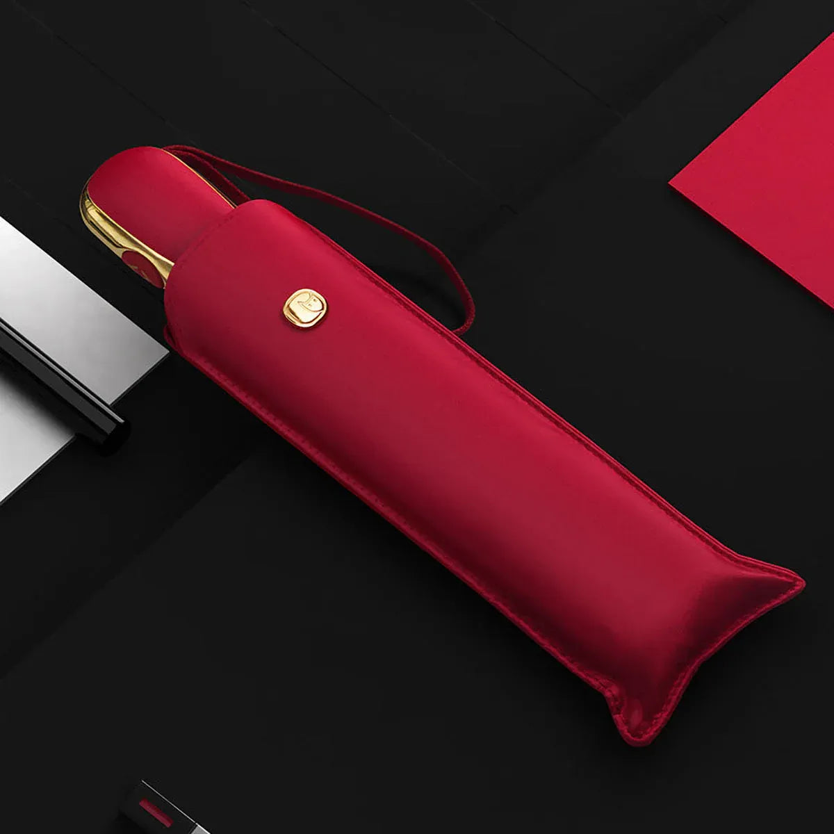 The elegant automatic travel umbrella for women in red, shown closed in its matching sleeve.