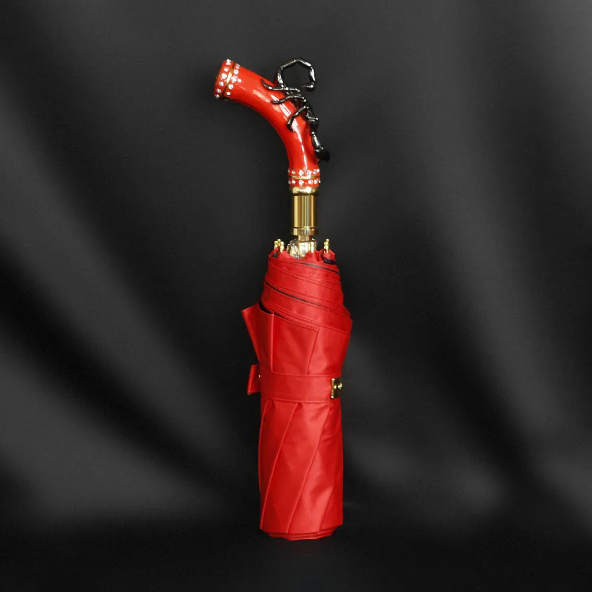 Profile view of the closed fancy red umbrella, showcasing the striking black scorpion handle.