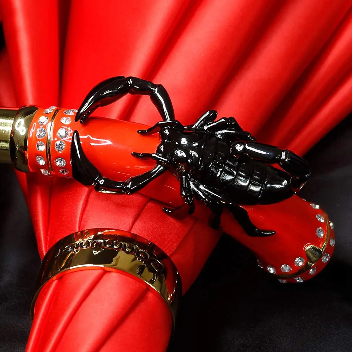 Detailed close-up of the black scorpion figure wrapped around the red jeweled handle.