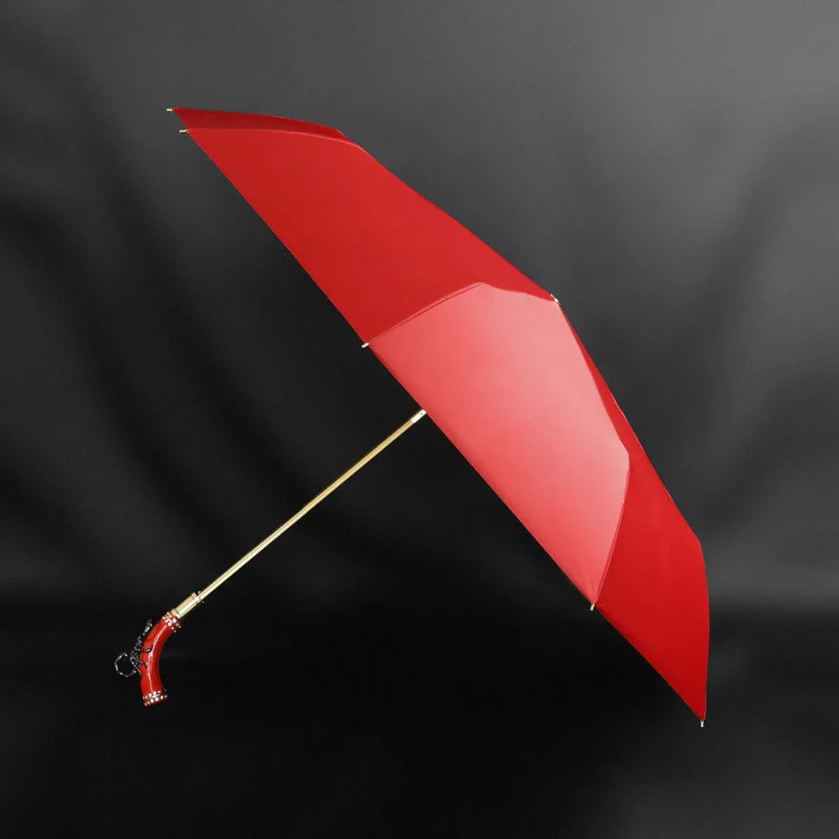 Full profile view of the open fancy red umbrella with the unique scorpion handle.