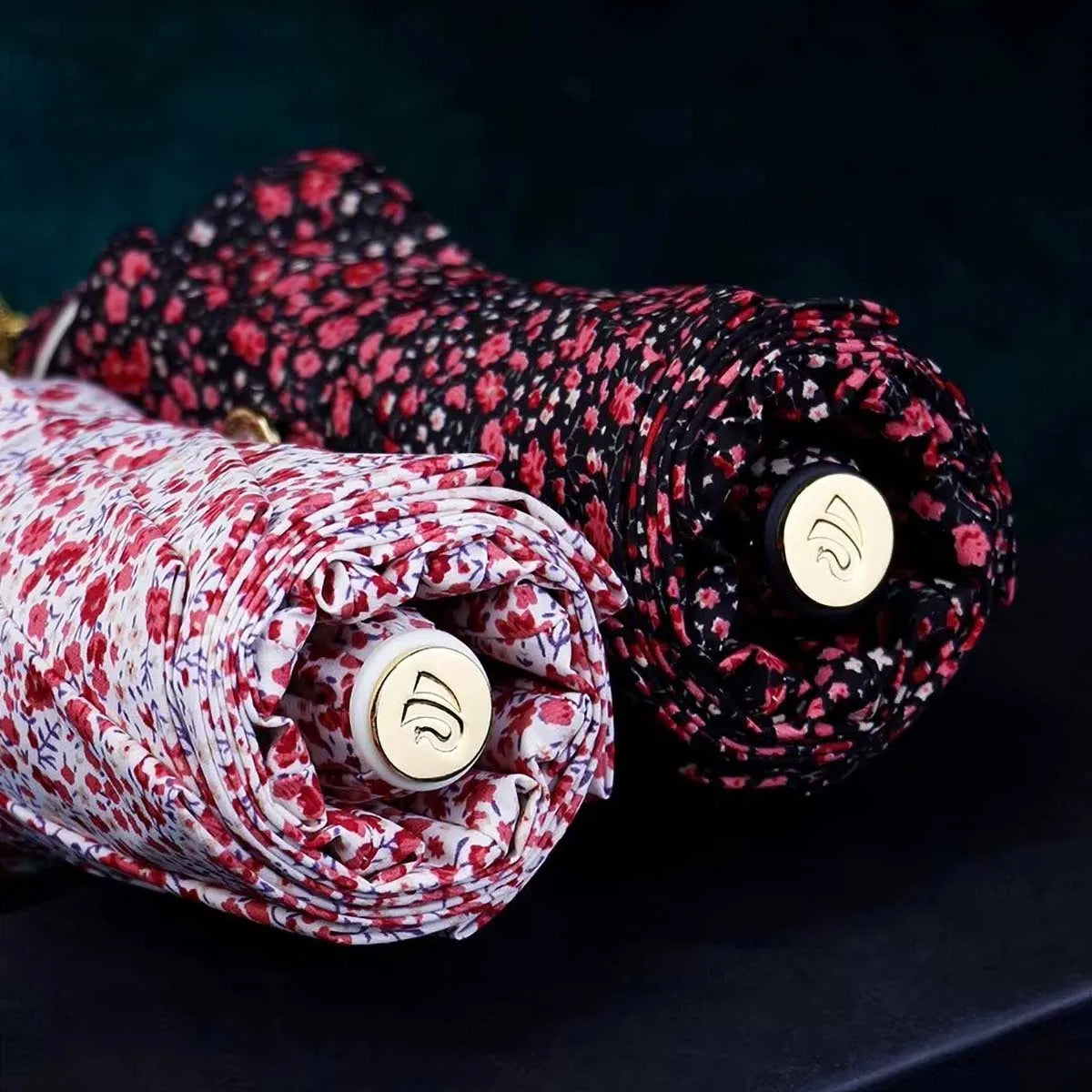Close-up showing the bottom end caps of the closed dark and light floral umbrellas.