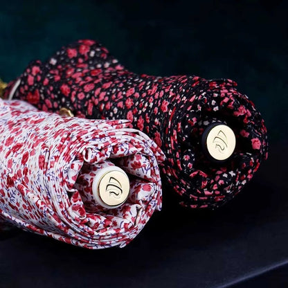 Close-up showing the bottom end caps of the closed dark and light floral umbrellas.