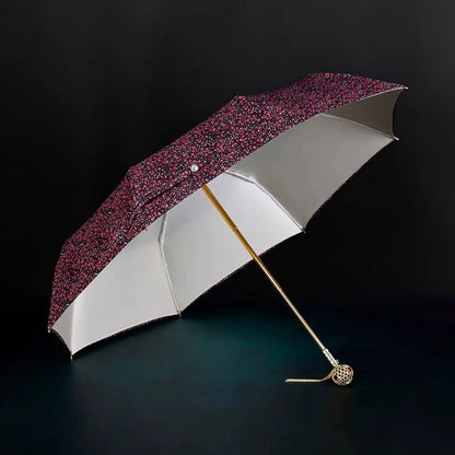 Full view of the open flower folding umbrella in the dark floral pattern with jeweled handle.