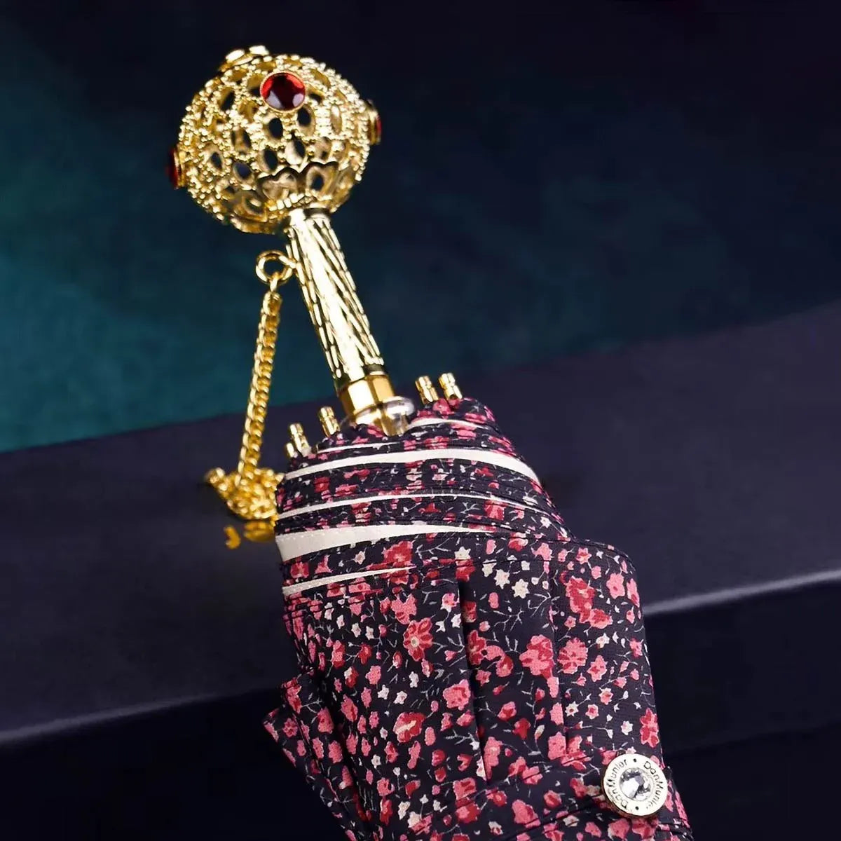 The flower folding umbrella with a jeweled handle, shown closed in a dark floral pattern.