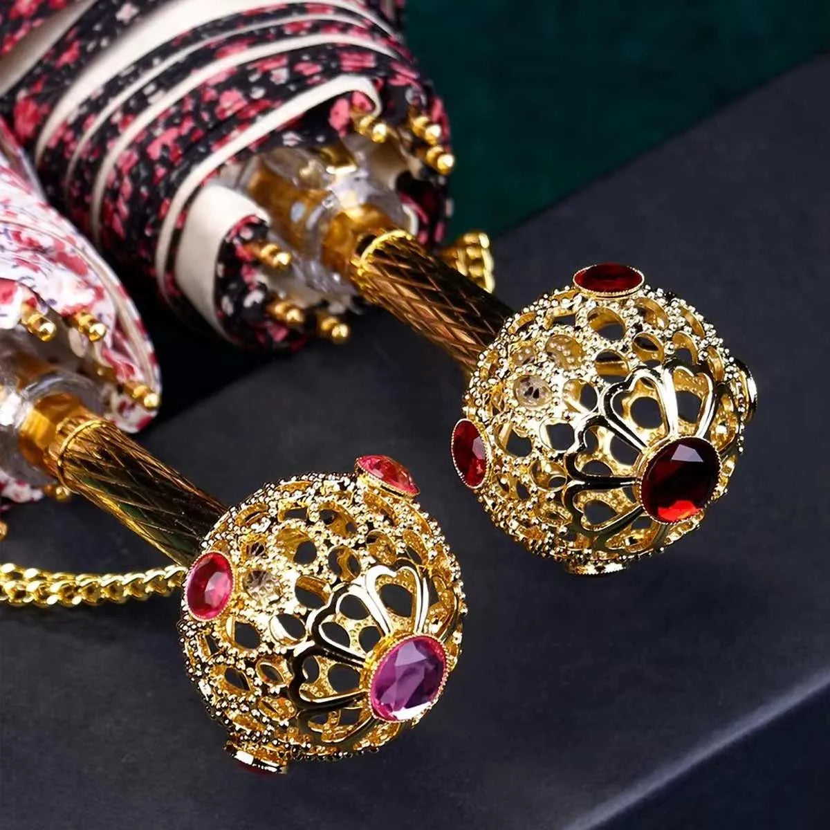 Close-up shot comparing the intricate golden jeweled handles of the flower folding umbrellas.