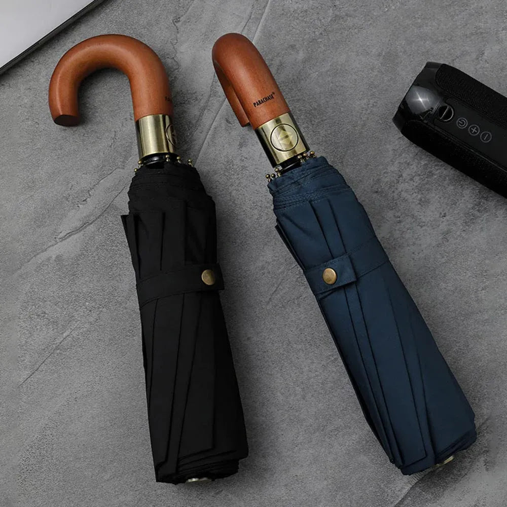 Lifestyle shot of the closed black and navy blue foldable automatic umbrellas with wood handles.
