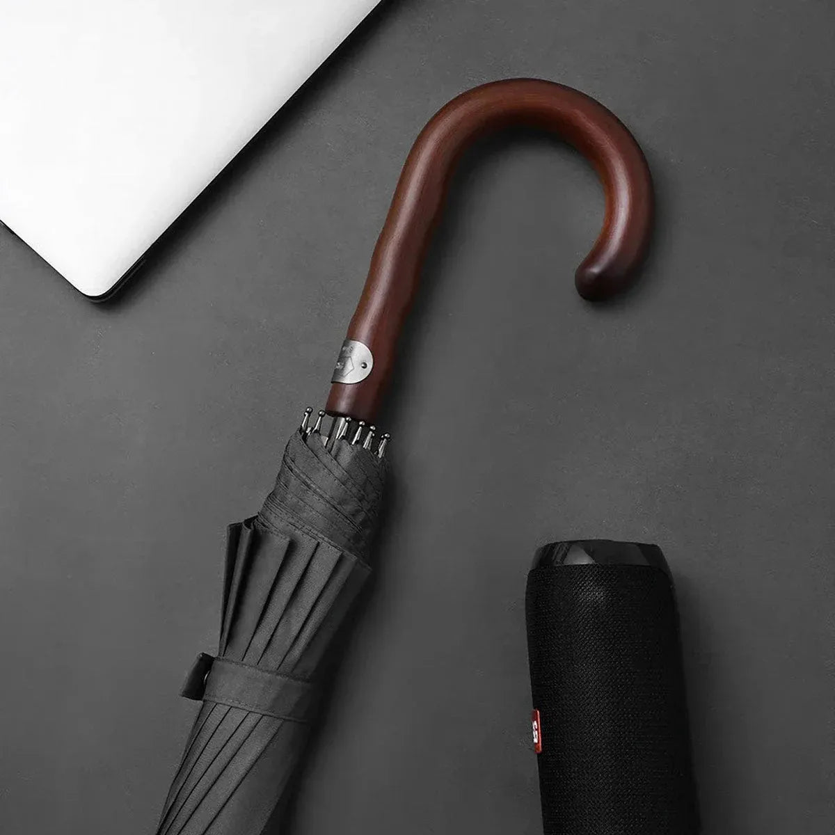 Lifestyle shot showing the closed grey Gentleman's umbrella handle next to a speaker.