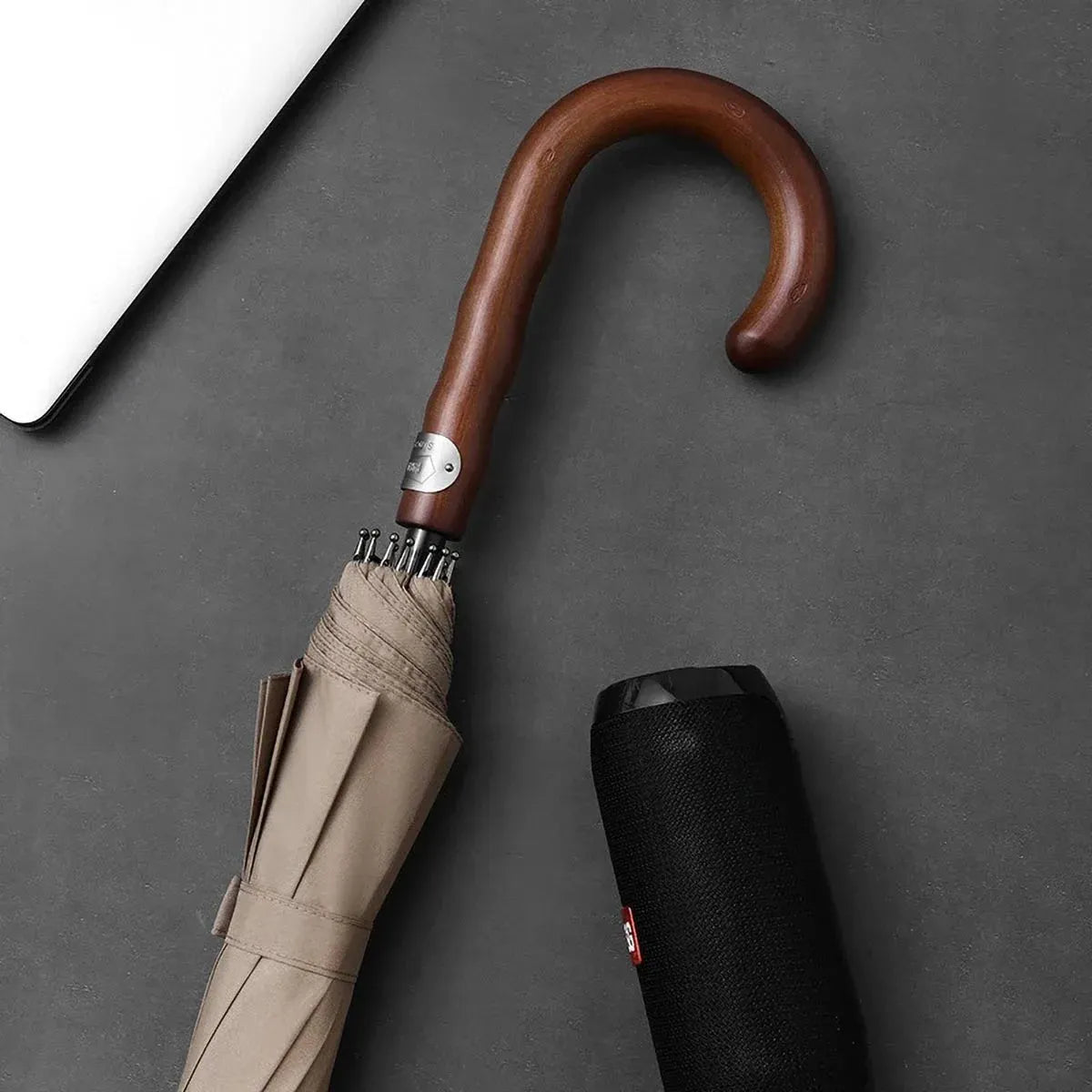 Lifestyle shot showing the closed khaki Gentleman's umbrella handle next to a speaker.