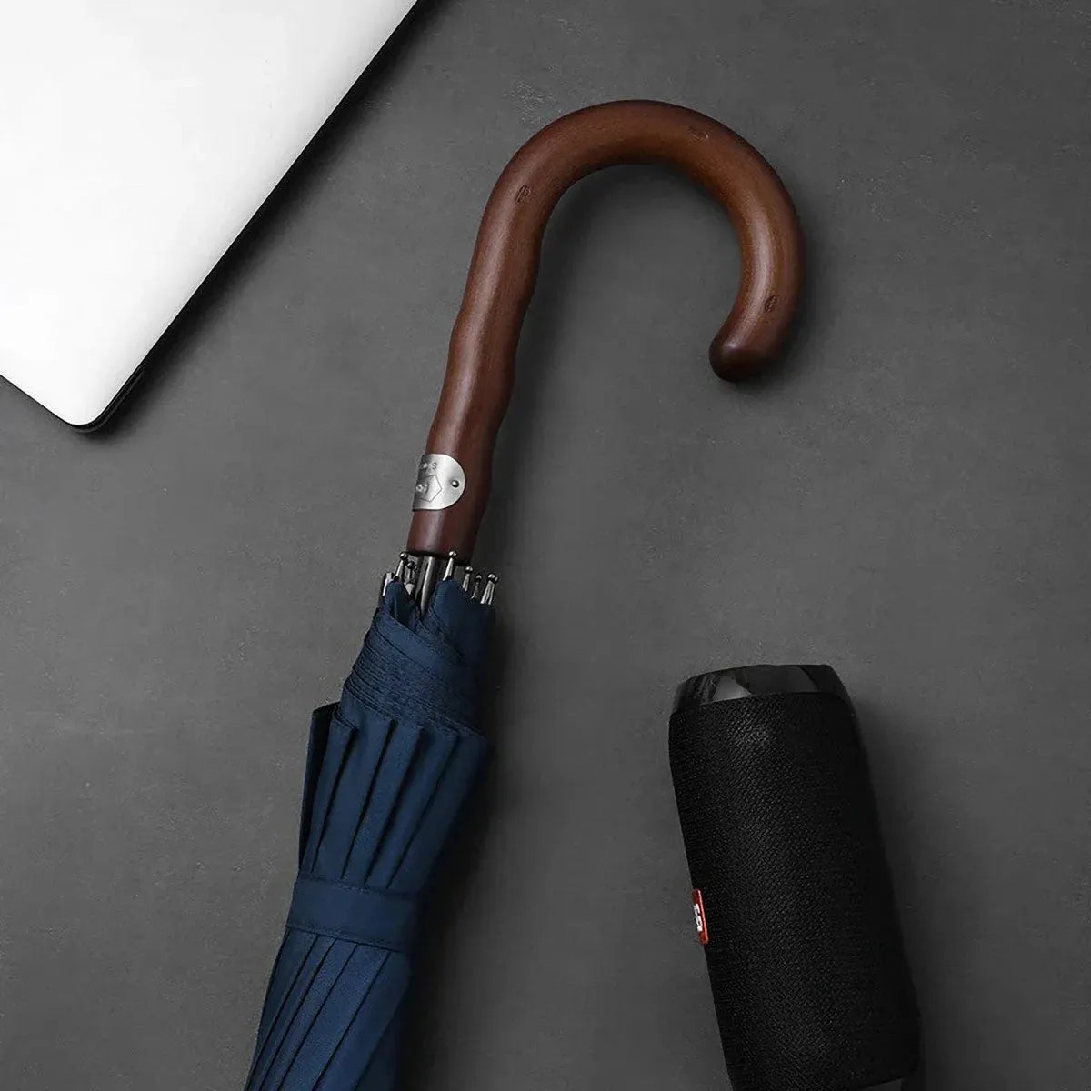Lifestyle shot showing the closed navy Gentleman's umbrella handle next to a speaker.