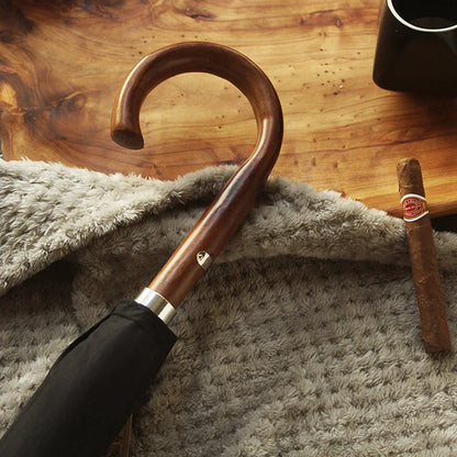 Close-up of the elegant wooden crook handle on the gents black umbrella.