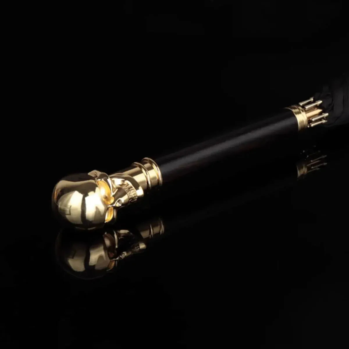Artistic shot of the Gold Skull Handle umbrella handle reflecting on a dark, glossy surface.