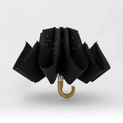 The black inverted umbrella shown in mid-close action, trapping water droplets inside.