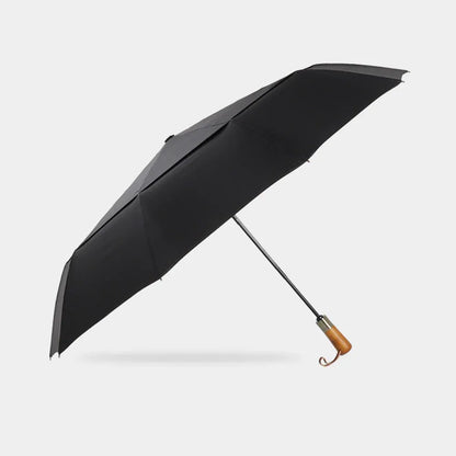 Full profile view of the open large automatic folding umbrella in black with wood handle.